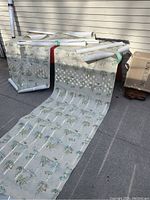 Seven wallpaper rolls laid on the ground showing floral and marine patterns with two wide rolls visible.