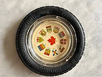Top view of the Goodrich Silver Cord tire advertising ashtray showing the central glass insert with provincial crests and red maple leaf.