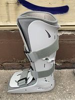 Side view of inflatable leg/ankle cast showing plastic shell, three adjustable velcro straps, and soft fabric lining.