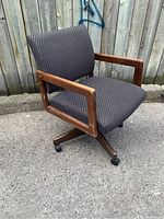 Side angle view of the office chair showing the wooden armrests, textured upholstery, and caster wheels under the wooden base.