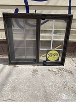 Front view of Pella window showing sliding window with screen on left and grid panel on right with Pella tag attached