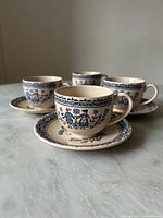 Four vintage cups and saucers set placed on table, showing all items in the set.