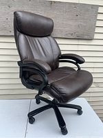 Front and side angle view of brown executive office chair with padded armrests, headrest, and caster wheels.