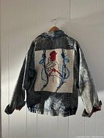 Back view showing hand-coloured artistic design on back panel with acid wash denim base.