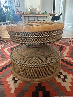 Side angle view of woven rattan pedestal table showing detail of geometric pattern and sturdy construction on decorative rug.