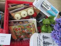 Photo of red box showing artificial purple flower stems and green leaves, decorative mini pumpkins, hole punch, and other crafting items on top.