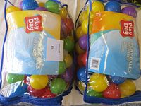 Two bags filled with colorful Play Day brand ball pit balls sealed in plastic bags with blue trim.