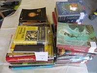 Photo showing two stacks of used books including Inkspell, Range Apprentice series by John Flanagan, and a cooking book on wild flowers among others.