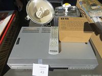 Sony DVD and VHS combo player with remote control on top. Clamp light with reflector and kitty water fountain box behind it.