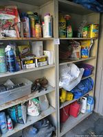 Two metal shelving units filled with assorted garden and household products. Rust visible on shelves. Various bottles, cans, and bags filling shelves.
