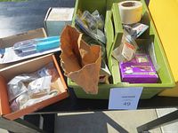 Green and brown plastic bins with various small garage hardware parts, masking tape, and boxed disposable gloves.
