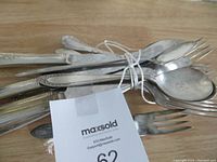 Photo of a tied bundle of assorted silver plated utensils including forks, spoons, and knives showing different handle designs and tarnishing