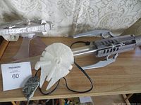 Millennium Falcon speaker with cord, plastic light saber, and small plastic meal toys on table