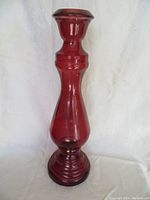 Front view of tall red glass vase on white background, shows curved body and flared top.