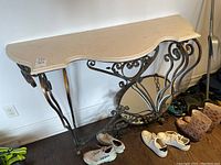 Front and angle views of the entry table showing the beveled faux marble top and ornate metal base with leaf and scroll motifs.