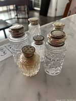 Group photo showing all six glass salt/pepper shakers with sterling silver rimmed tops on marble surface