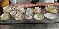 Overview of the assorted teacups, saucers, soup bowls, gravy boat and plates showing mismatched sets and variety of patterns