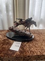 Front view of Native American themed mixed media sculpture showing horse and two figures with action pose on black base.