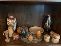 Full view of all decorative items arranged on shelf including vases, wooden bowls, containers, and pottery.