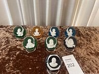 Full set of 8 Baccarat crystal paperweights displayed with various cobalt-colored bases and white relief portraits.