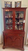 Full front view of wood hutch with upper glass cabinet and lower storage