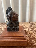 Front and right side angled view of the bronze Native American Indian bust showing detailed facial features and feather headdress.