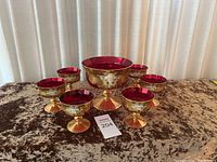 Full view showing one large compote bowl and six smaller stemmed glasses arranged on a velvet surface.