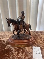 Full front view of resin sculpture on wood base against curtain background