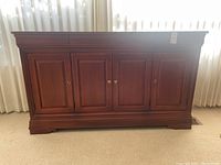 Front view of the wooden sideboard with four doors and brass handles