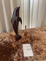 Photo showing the dolphin, duck, cat, and lion wood carved figurines on a velvet surface.
