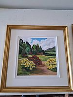 Frontal view of the framed acrylic painting showing the landscape with flower bushes, trees, hills, and sky.