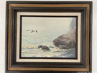 Full view of framed acrylic on canvas seascape painting featuring waves, rocks, and a flying seagull.