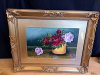 Frontal view of the gilt-framed watercolour still life featuring red and pink roses in a yellow vase on a wooden surface.