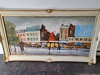 Framed oil painting showing Paris street scene with Moulin Rouge and several pedestrians under an overcast sky.