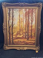 Full view of framed oil painting depicting autumn forest scene with tall trees and warm tones.
