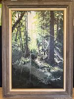 Overall front view of painting in wood and gold-tone frame showing forest scene with sunlight