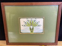 Full view of the teak-framed woodcut print featuring a stylized peacock with a green mat.