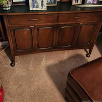 Front view of dark wood sideboard showing two drawers and four curved panel doors