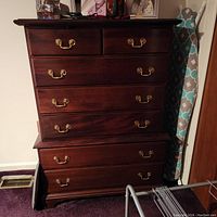 Front view of a traditional style cherry wood dresser with five drawers and brass handles. Shows dark wood finish and some wear marks.