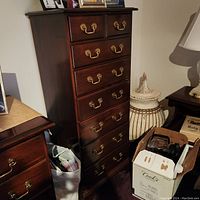 Angled front view of eight-drawer cherry wood tall dresser in room