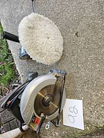 Skilsaw 7 1/4 inch circular saw with visible blade and metal body with power cord; buffer with wool polishing pad behind saw.