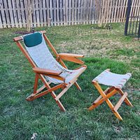 View of one Nags Head Cumaru captain's chair with matching folding footstool on grass, showing folding wooden frame and woven white rope seat with green pillow.