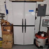 Front view of closed garage storage cabinet showing two ribbed, light grey doors with black vertical handles and black base.