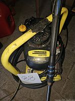 Top view of the Karcher power washer showing the yellow metal frame, engine, and attached hose and spray wand with taped handle.