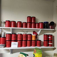 Wide view of shelves with multiple red containers labeled with various hardware contents such as bolts, nails, washers, and screws.