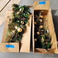 Two 36-inch gold elegance wall sconce swag garlands in their original boxes showing decorations and packaging.