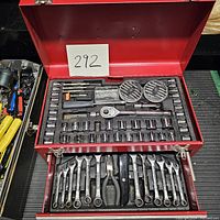 Open red metal toolbox showing socket wrench ratchet, multiple socket sizes, hex keys, and accessories in top compartment