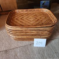 Stack of 11 woven rattan serving trays showing the side profile and thickness.