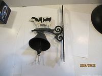 Side view of cast iron bell with cow figure and mounting bracket on white background