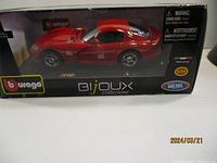 Front and side view of Burago die cast red Viper model car inside original packaging box showing branding and scale 1:24